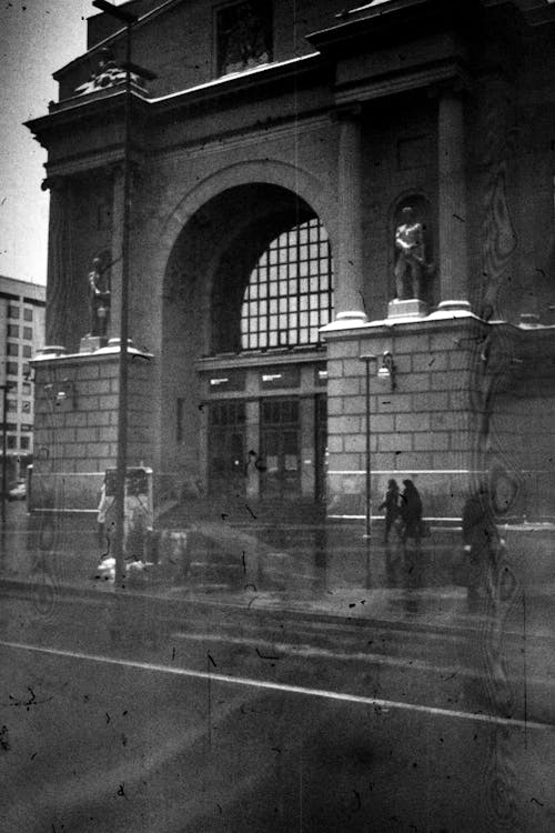 Grayscale Photo of People Walking on the Sidewalk Near a Building