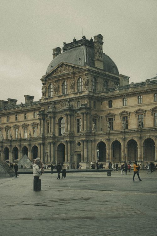 Free Atmospheric view of the Louvre Museum facade with visitors, Paris, France. Stock Photo