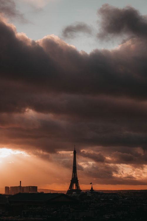 Free A breathtaking view of the Eiffel Tower under dramatic cloud formations during sunset in Paris, France. Stock Photo