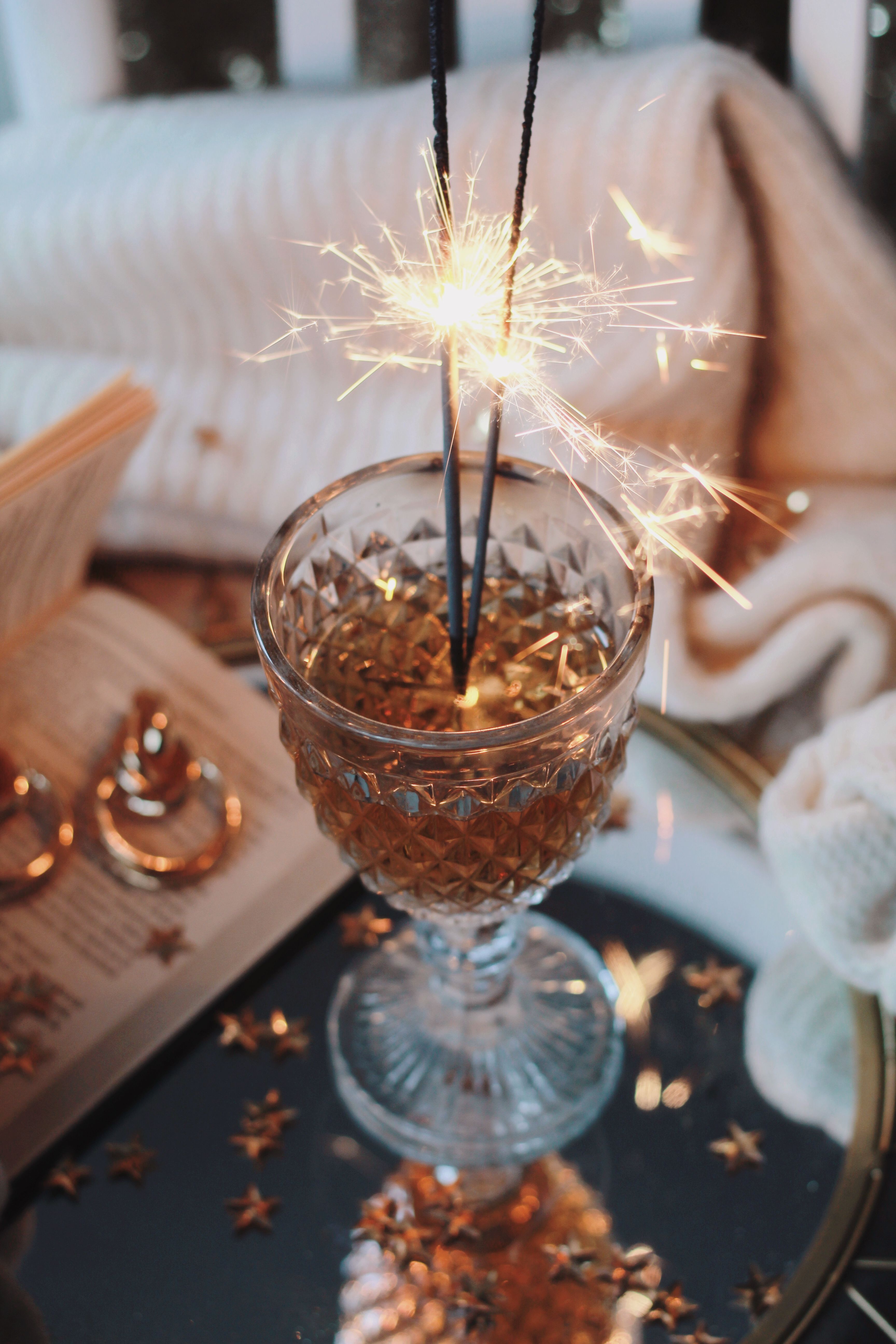 A sparkler shines brightly in a crystal glass, capturing festive warmth and elegance.