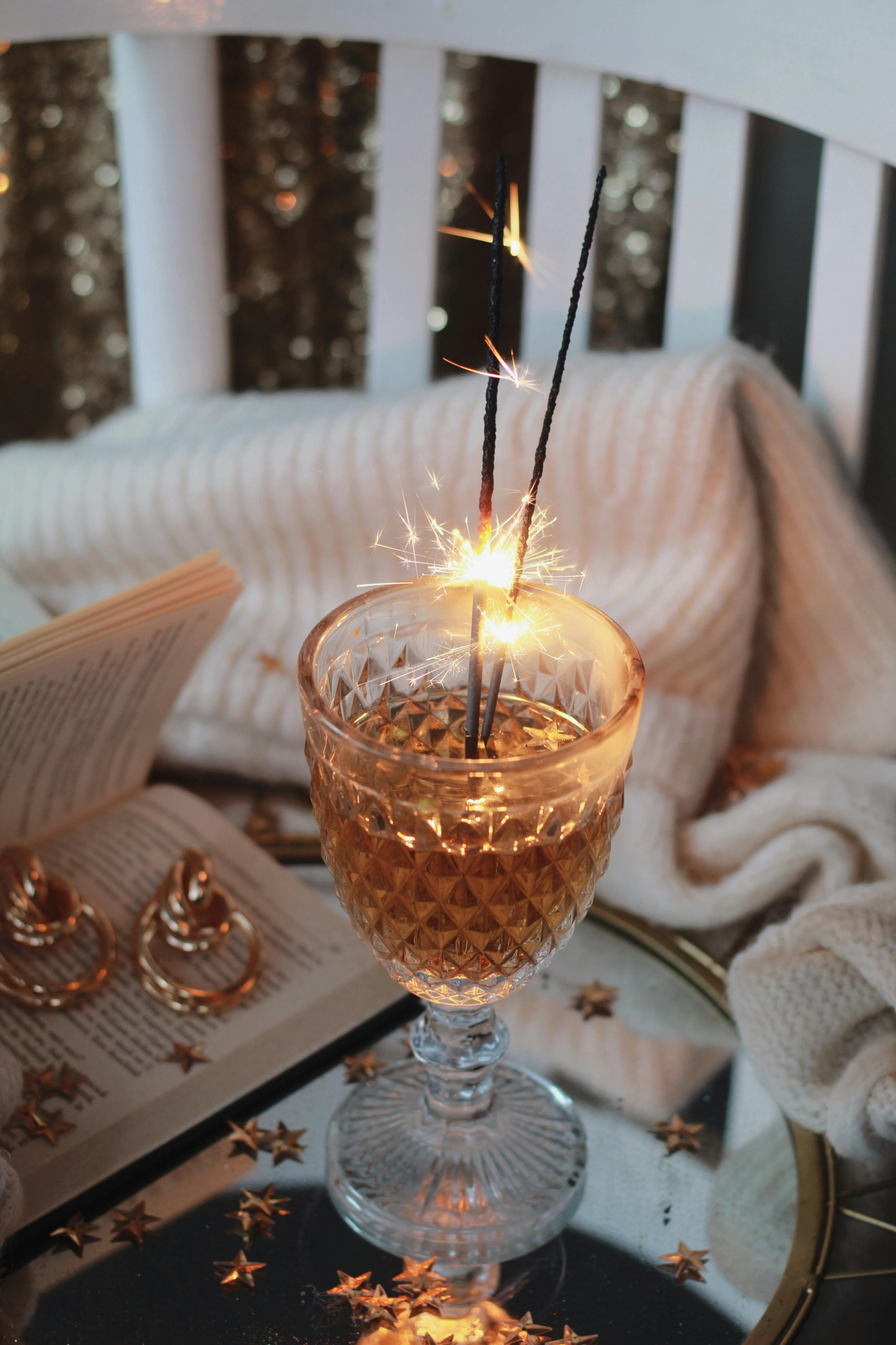 Festive scene with sparklers in a wine glass, creating a cozy holiday ambiance.