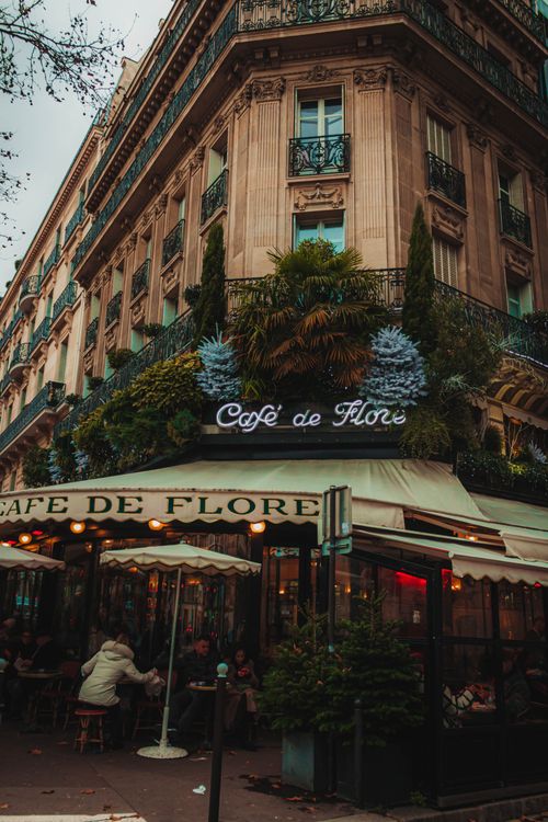 Free Charming view of Café de Flore with Parisian architecture and vibrant foliage, capturing urban elegance. Stock Photo