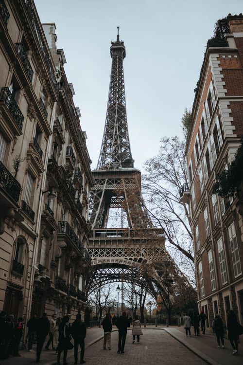 Free Low angle view of the Eiffel Tower framed by historic buildings on a Paris street. Stock Photo