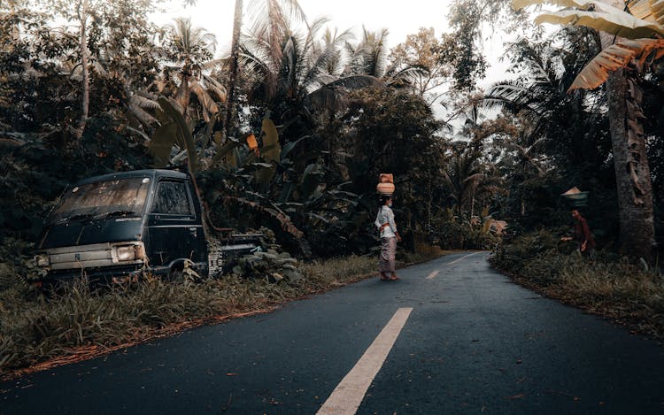 People Walking On The Road Near An Abandoned Truck On The Side Of The Road