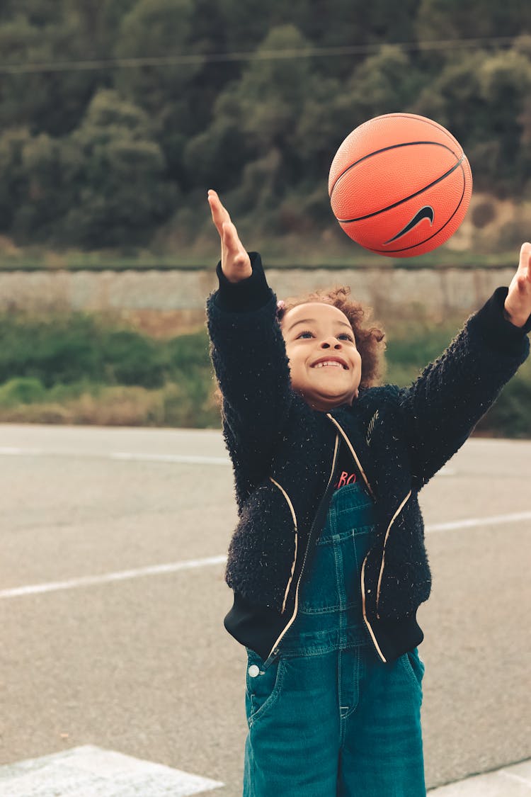 A Kid In Black Jacket Playing Basketball