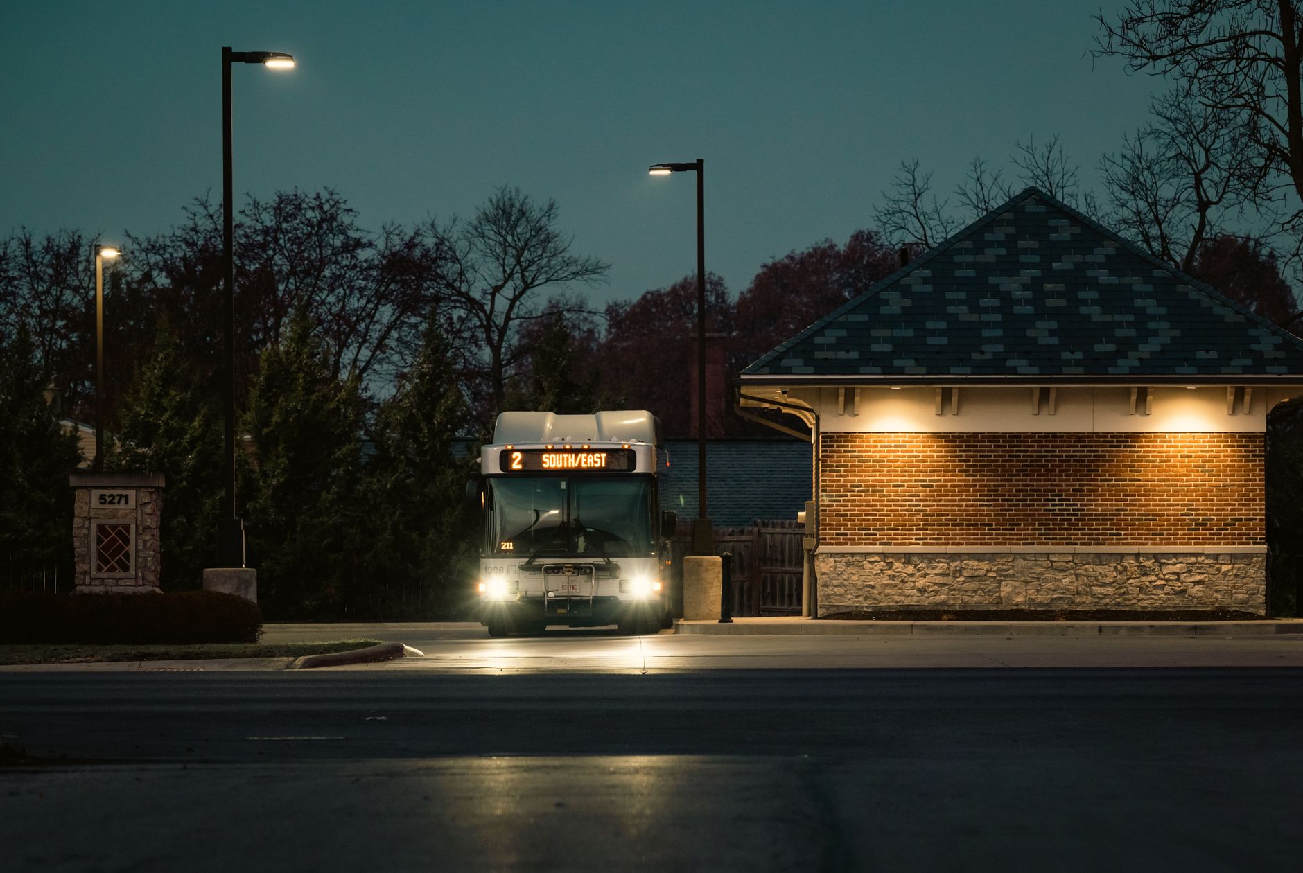 Illuminated public bus on a quiet city street during twilight hours.