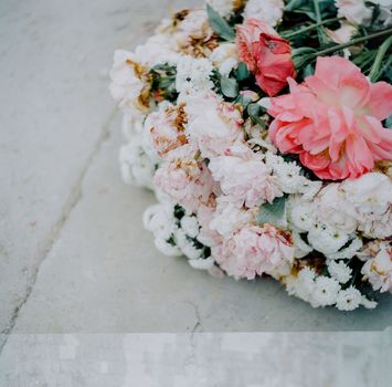 A beautifully arranged pink and white floral bouquet rests on a concrete surface, showcasing vivid petals.