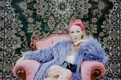 Woman with Pink Hair in a Fur Coat Sitting on a Pink Chair