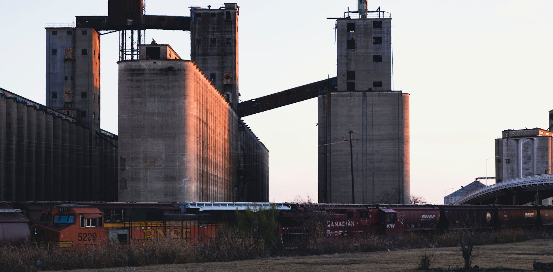 Sunlit grain silos and freight trains in Fort Worth, Texas, highlighting industrial architecture.