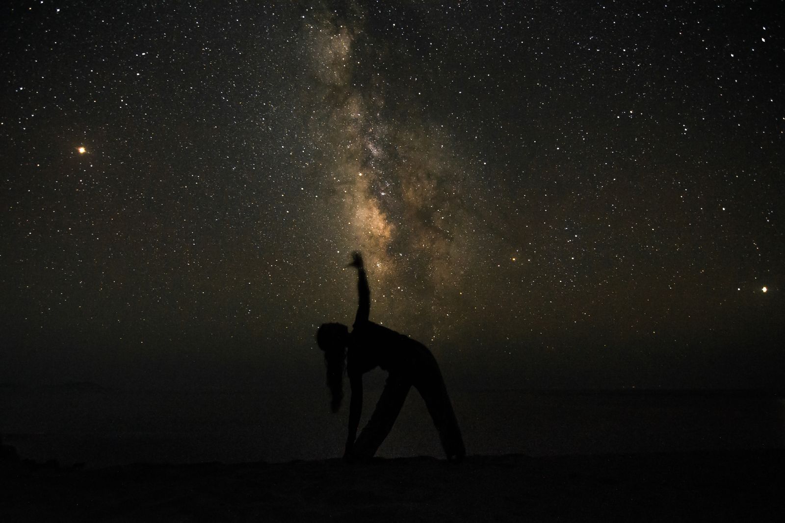 Silhouette holding a standing pose beneath a night sky — photo by Kostas Exarhos on Pexels