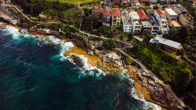 Stunning aerial shot of Bondi's coastline with homes and rugged cliffs, NSW, Australia.