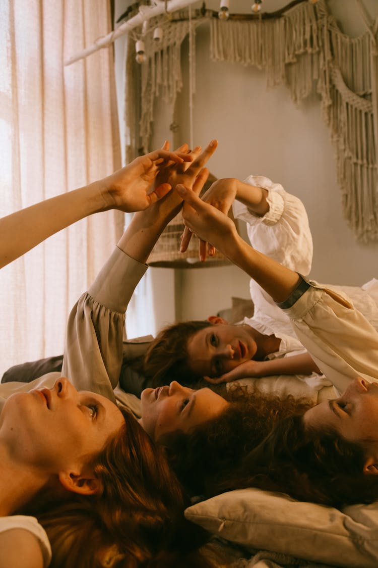 Teenage Girls Laying Down Holding Outstretched Hands