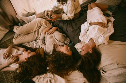 Free A group of teenage girls enjoys a relaxing sleepover, lying down indoors with natural light. Stock Photo