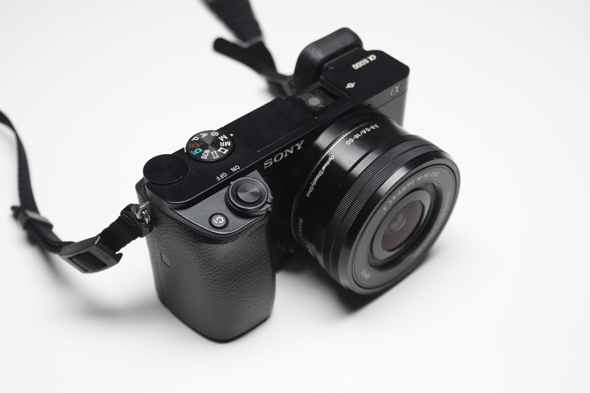 Detailed image of a modern camera with lens on a white surface, perfect for photography themes.