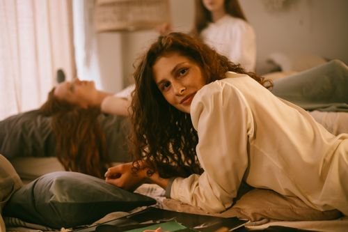 Free Redheaded women lounging indoors, one smiling at the camera in a relaxed setting. Stock Photo