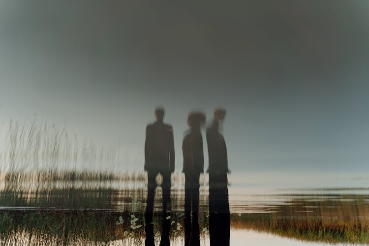 People Silhouette Reflected In Pond