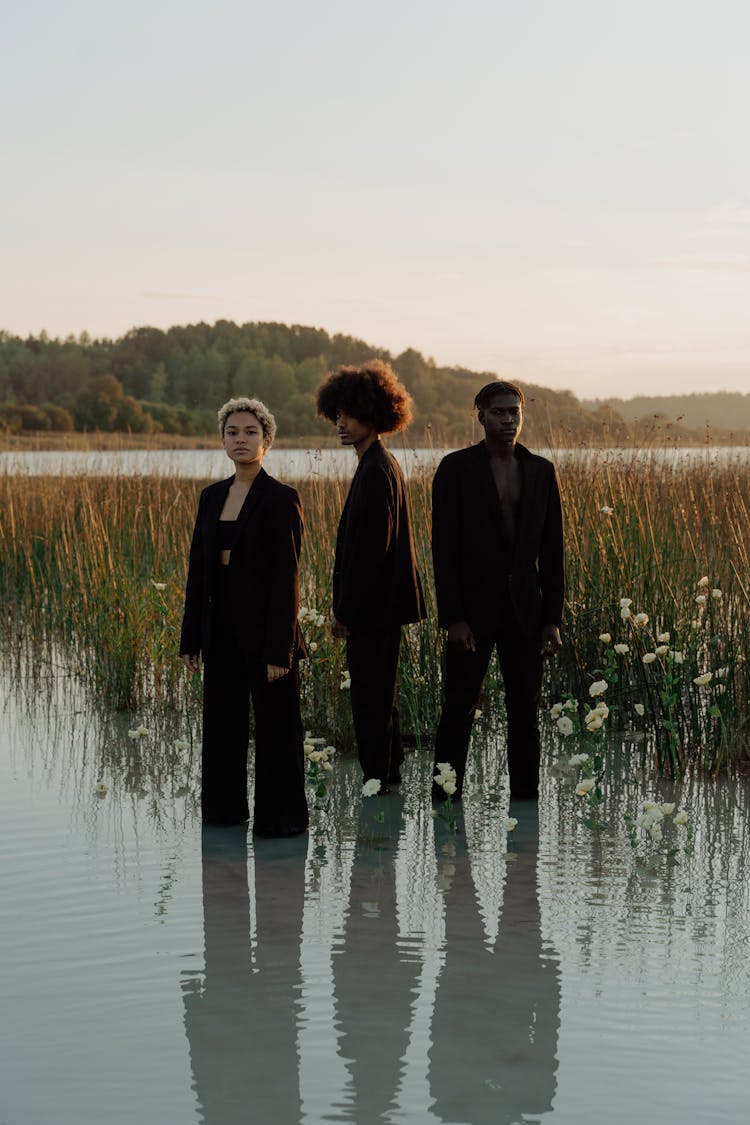 People In Black Suit Standing On Wetland 