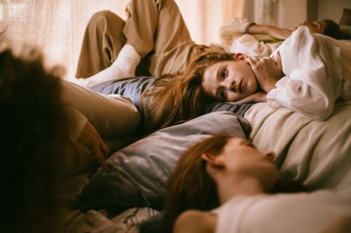 Free Teenagers enjoying a relaxed sleepover, lying in a comfortable and cozy bedroom setting. Stock Photo