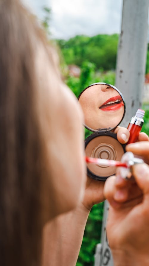 Free A Reflection of a Person Applying Red Lipstick on Her Lips Stock Photo