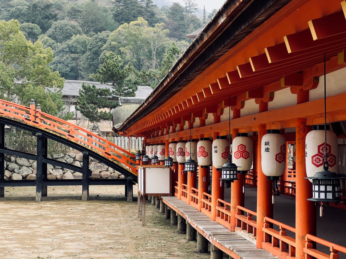 Wooden bridge and stone lanterns leading toward Itsukushima Shrine