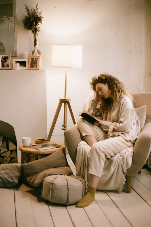 Woman Sitting in Armchair Reading Book