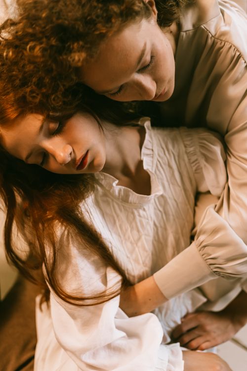Free Two women embracing, eyes closed, conveying peace and comfort in warm lighting. Stock Photo