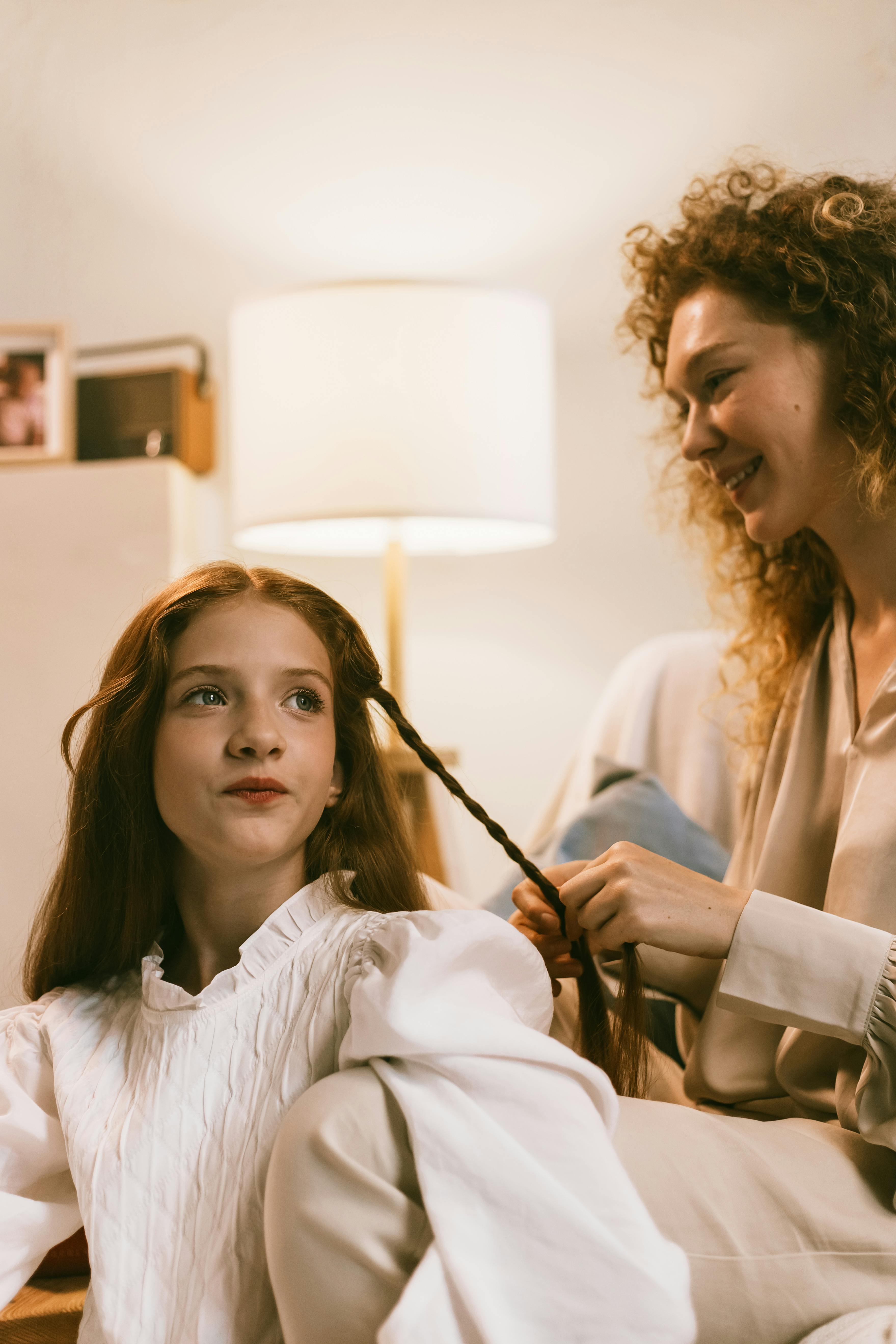 woman braiding teenage girl hair