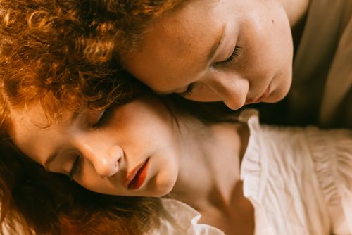 Free A serene close-up portrait of two women embracing with eyes closed, conveying warmth and closeness. Stock Photo
