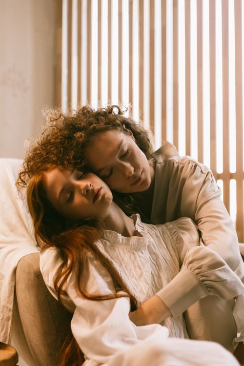 Free Two women embracing peacefully in a warm, inviting home interior. Stock Photo