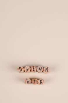 Inspirational 'Dream Big' message with wooden blocks on a minimalist beige background.