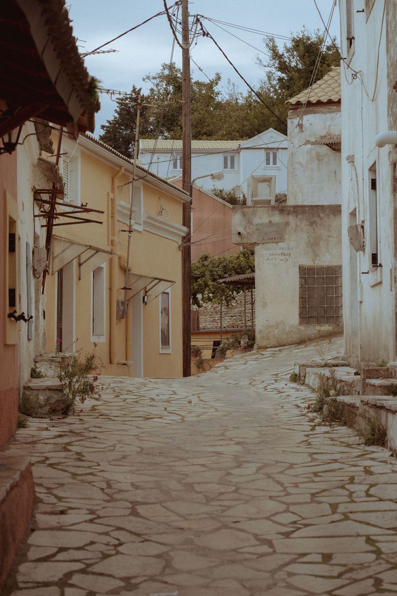 Explore the quaint charm of a narrow cobblestone alley in a traditional Greek village in Corfu