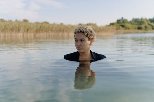 Calm portrait of a woman standing in clear lake water, surrounded by nature.