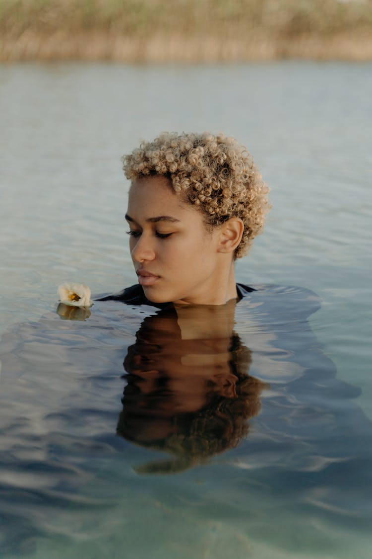 Woman Swimming On A Lake Beside A Floating Flower