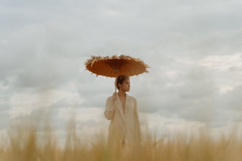 Woman in Beige Coat Holding an Umbrella Looking Sideways 