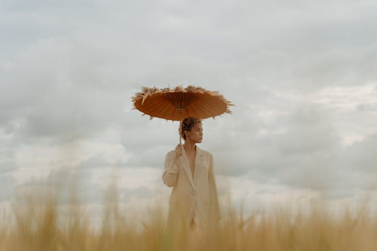 Woman In Beige Coat Holding An Umbrella Looking Sideways 