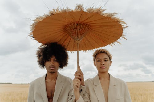 Man and Woman in Beige Coat Holding an Umbrella 