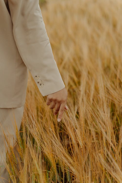Free Person in White Long Sleeve Shirt and White Pants Standing on Brown Grass Field Stock Photo