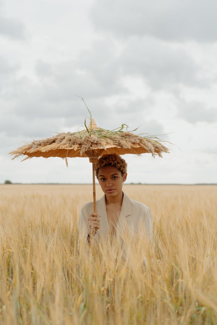 Woman Holding Umbrella On Brown Field Under Cloudy Sky 