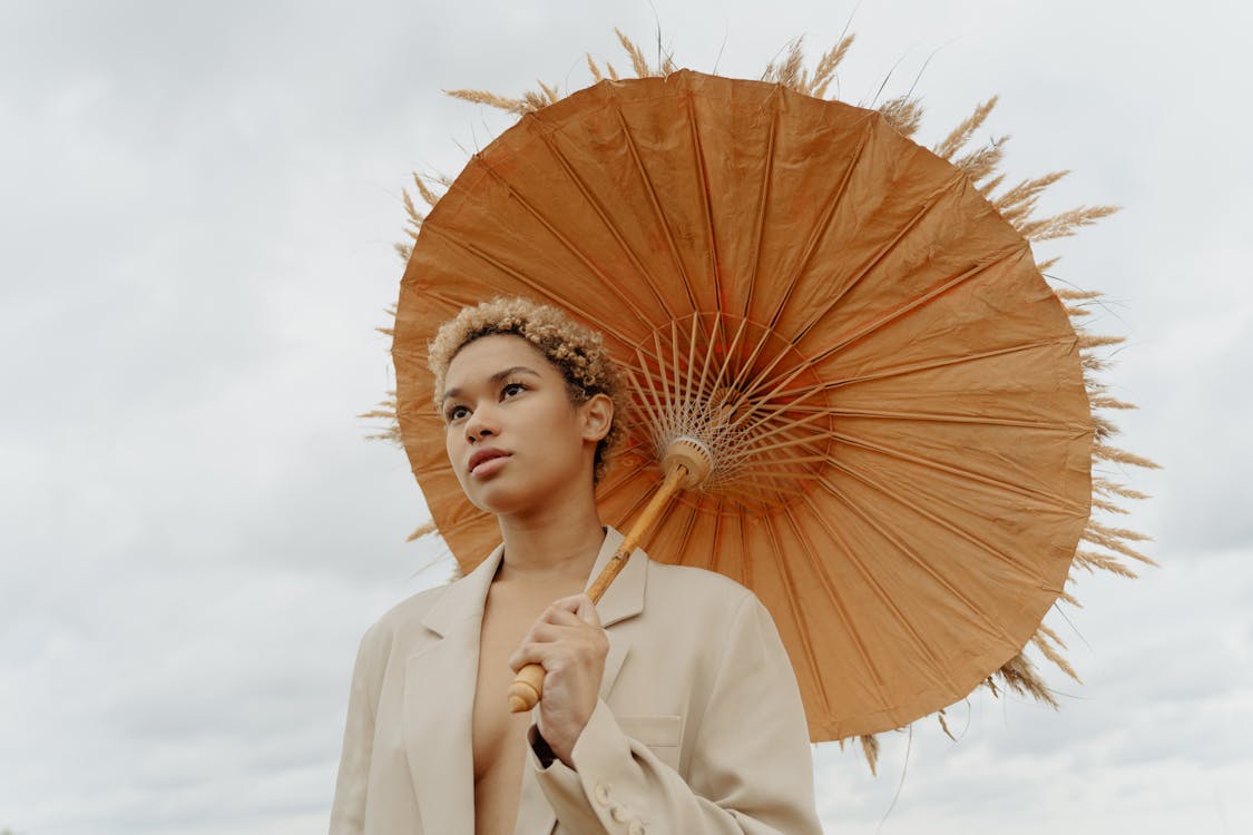 Low-Angle Shot of a Woman in Beige Coat Holding a Brown Umbrella