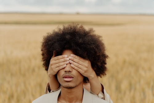 A Person Covering a Young Man's Eyes