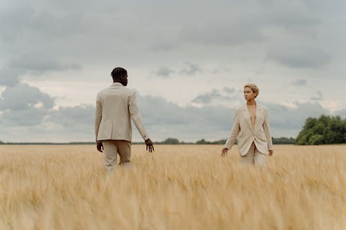 Free Man and Woman Holding Hands While Walking on Brown Grass Field Stock Photo