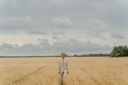 Free Woman in White Long Sleeve Dress Standing on Brown Grass Field Under White Clouds Stock Photo