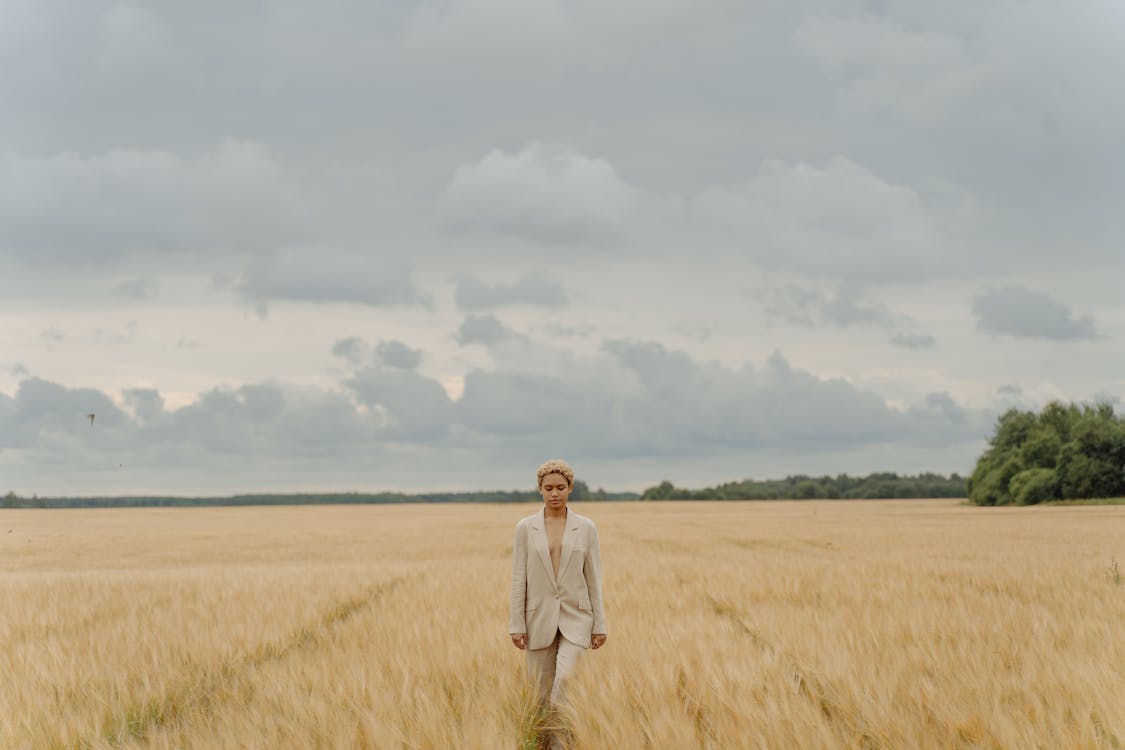 Woman in Beige Suit Standing on Brown Grass Field