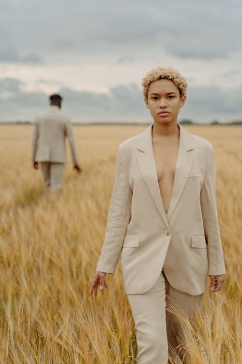 Woman in Beige Suit Standing on Brown Grass Field