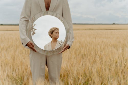 Elegant Man Holding a Mirror on a Field