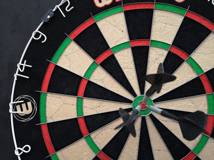 A Close-up Shot Of A Dartboard With Darts On The Bullseye 