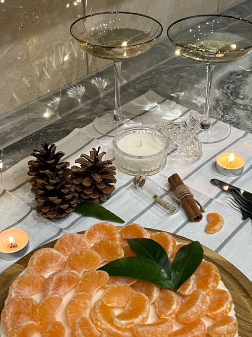 Free Elegant still life featuring mandarin dessert, pine cones, candles, and wine glasses creating a festive atmosphere. Stock Photo