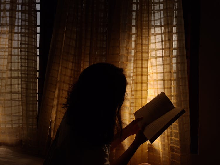 Woman Reading Book In Dark Room