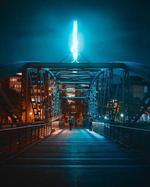 Free A vibrant city bridge at night with people walking under glowing lights. Stock Photo