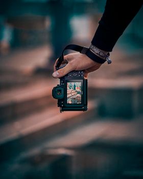 A close-up shot of a camera held in hand, capturing an urban scene on its display screen.